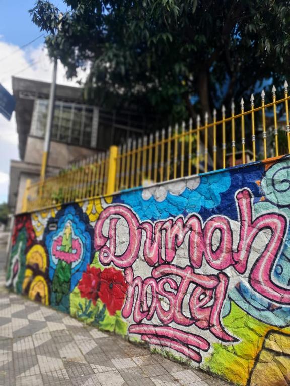a wall covered in graffiti with the words unhappy mess at Hostel Dumah in Sao Paulo