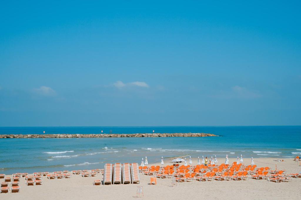 uma praia com cadeiras e guarda-sóis e o oceano em Roxon Sea Sand Bat Yam em Bat Yam