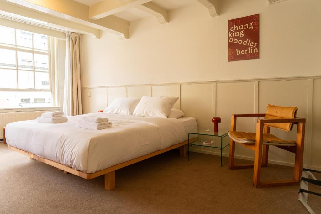 1 dormitorio con 1 cama blanca grande y 1 silla en hotel calisto en Ámsterdam