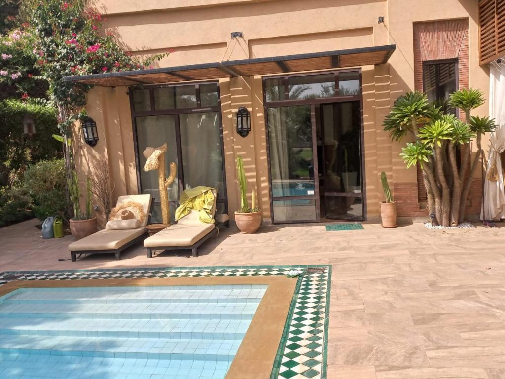 einen Pool mit zwei Stühlen und ein Haus in der Unterkunft Villa rouge in Marrakesch
