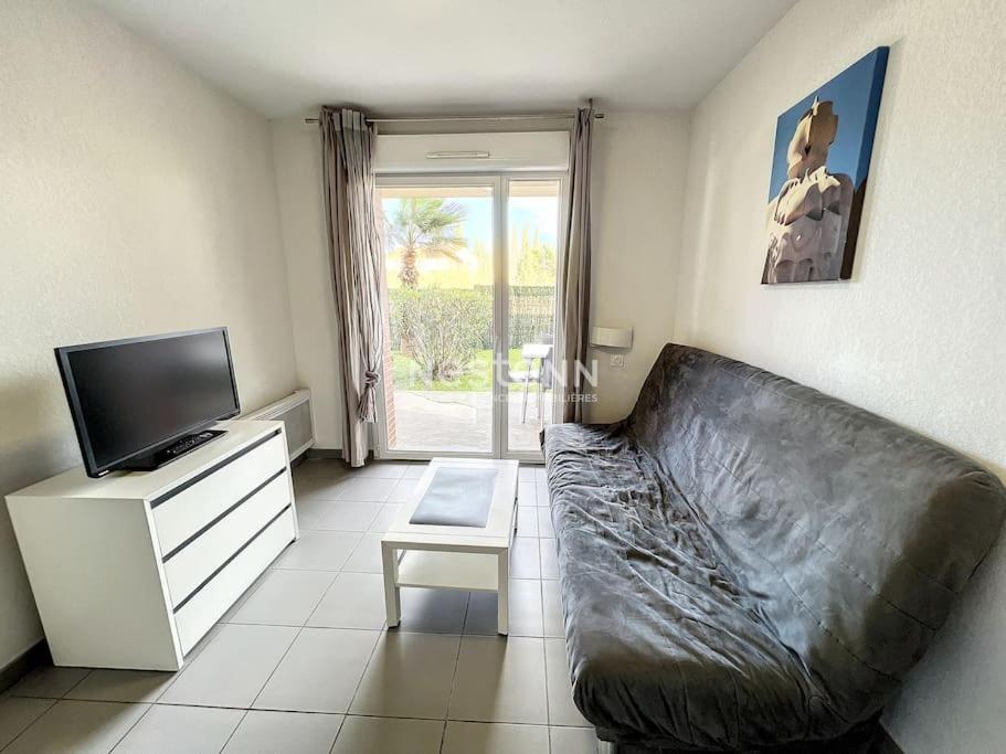 uma sala de estar com um sofá de couro e uma televisão em Appartement 4 couchages avec piscine em Argelès-sur-Mer