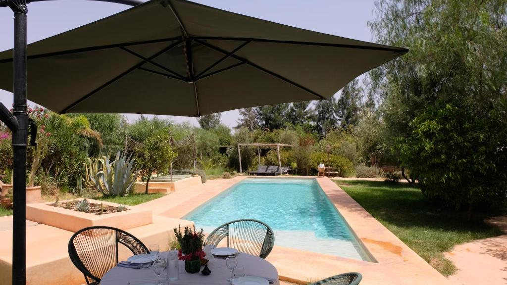 een tafel met een parasol naast een zwembad bij Asnouss in Marrakesh