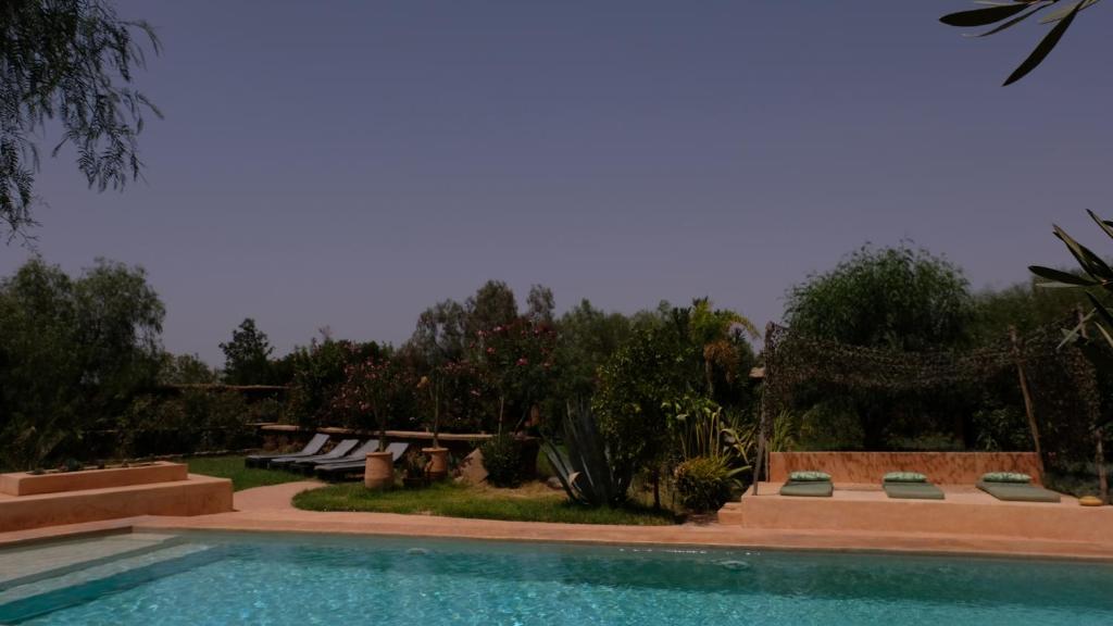 uma piscina num quintal com bancos e árvores em Asnouss em Marrakech