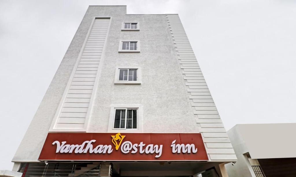 un edificio blanco alto con un letrero rojo. en vardhan @stay inn, en Tirupati