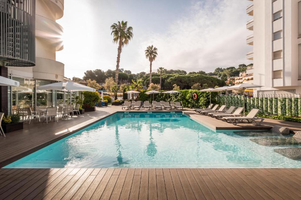 a swimming pool in a hotel with chairs and umbrellas at ALEGRIA Fenals Mar in Lloret de Mar