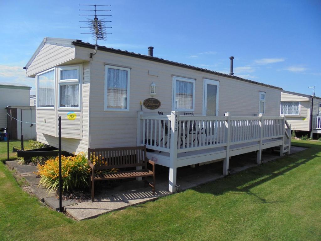 a small white house with a porch and a yard at Golden Sands: Richmond GS:- 6 berth, Blow heated, Access to the beach in Ingoldmells