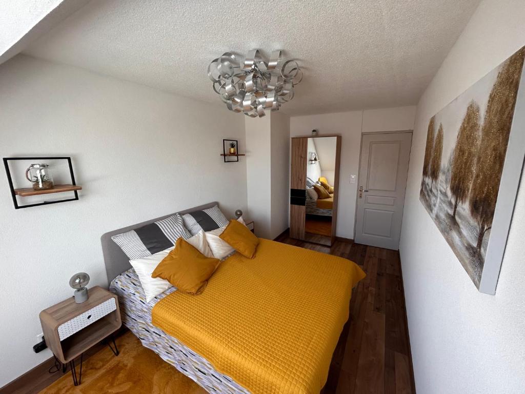 um quarto com uma cama amarela e um lustre em LE NOUVEAU VAUBAN em Colmar