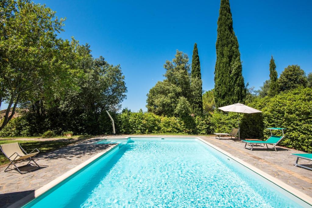 a swimming pool with two chairs and an umbrella at Glicine Apartment Podere Giardino in Montalcino