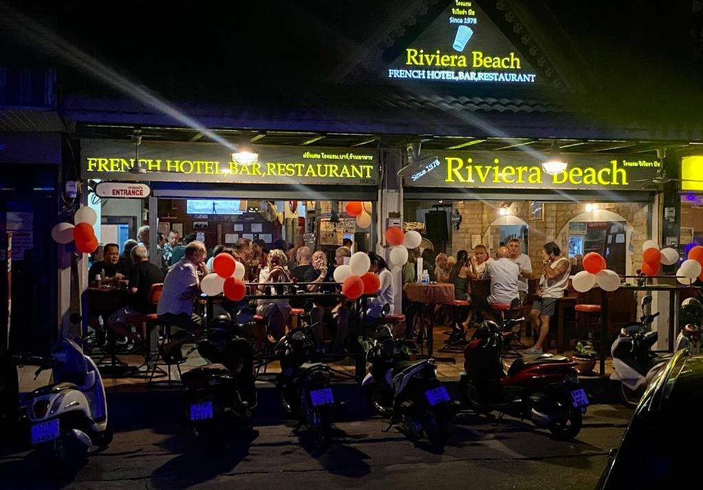 un grupo de personas sentadas en un bar con globos rojos y blancos en Riviera Beach, en Pattaya central