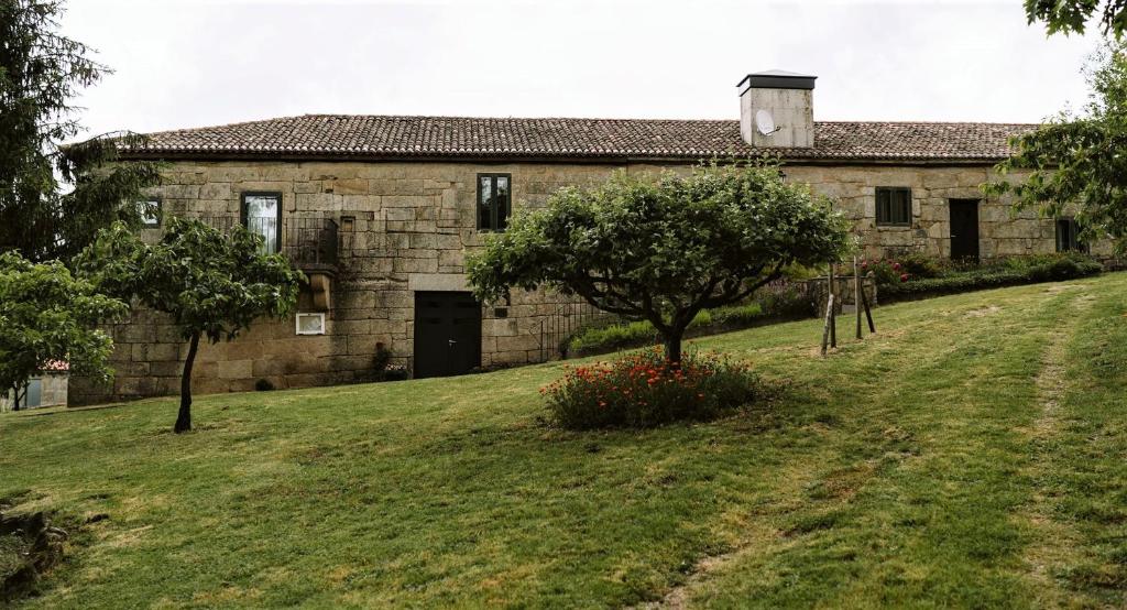 an old stone building with a tree in front of it at Casa Rural Rectoral de Armariz in Nogueira de Ramuin