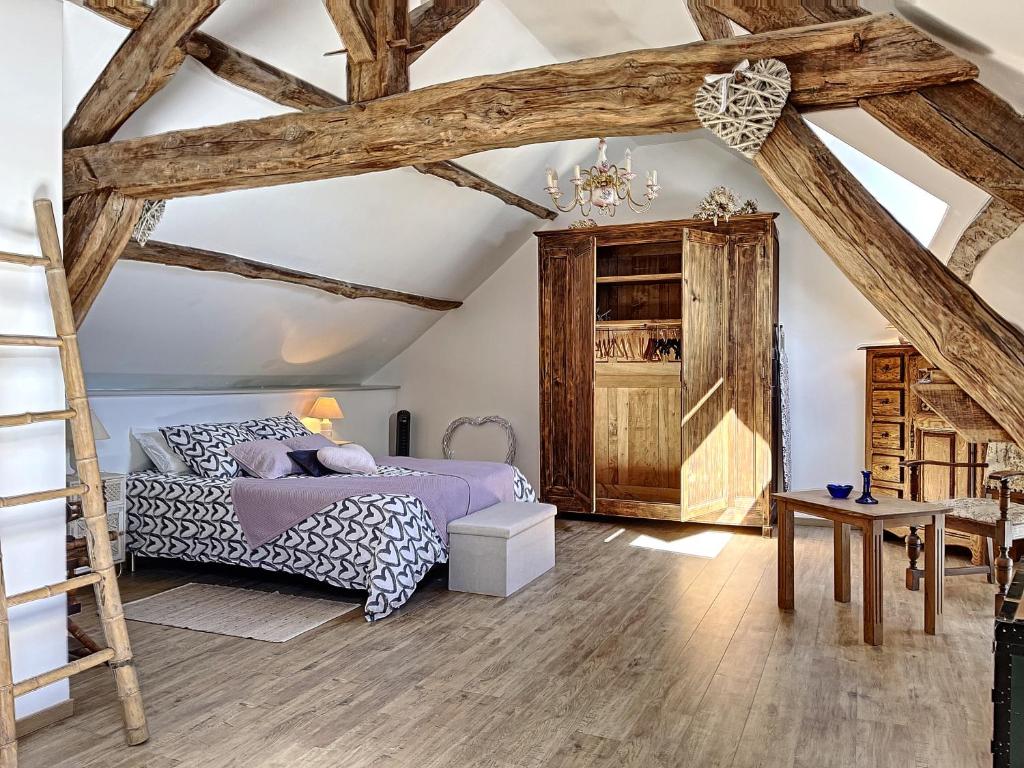 una camera da letto con soffitti in legno, un letto e una scala a pioli di Maison de vacances au cœur de la nature a Sully