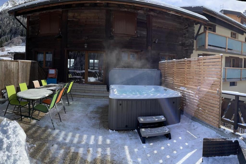 a hot tub on a patio in front of a building at La Grange à Coco avec jacuzzi in Bourg-Saint-Pierre