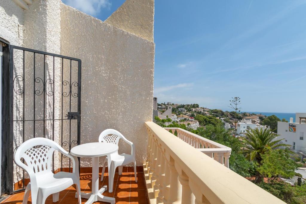 einen Balkon mit weißen Stühlen und einem Tisch auf dem Balkon in der Unterkunft Bungalow Calle Altea in Aigues