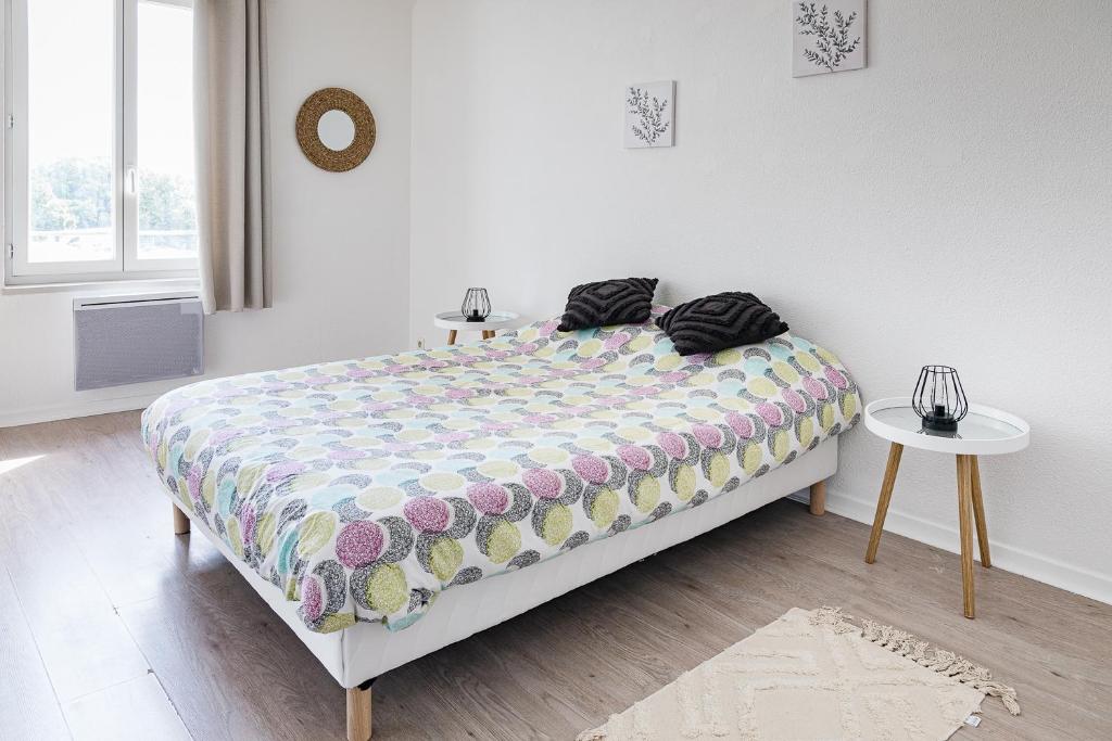ein Schlafzimmer mit einem Bett mit einer Bettdecke und einem Tisch in der Unterkunft Le Beauvoir in Saint-Marcellin