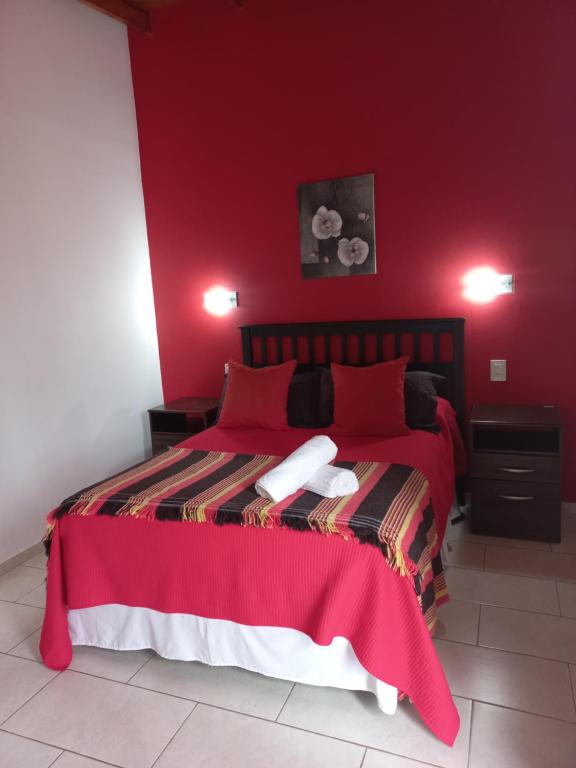 czerwona sypialnia z łóżkiem z czerwonymi ścianami w obiekcie AltoRojo w mieście Villa Elisa