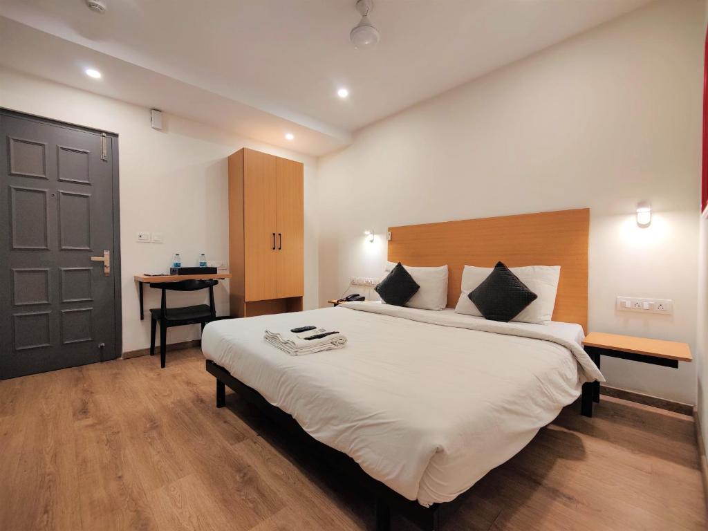 a bedroom with a large bed and a desk at Hotel Bakya Slot - Maraimalai Nagar in Chengalpattu