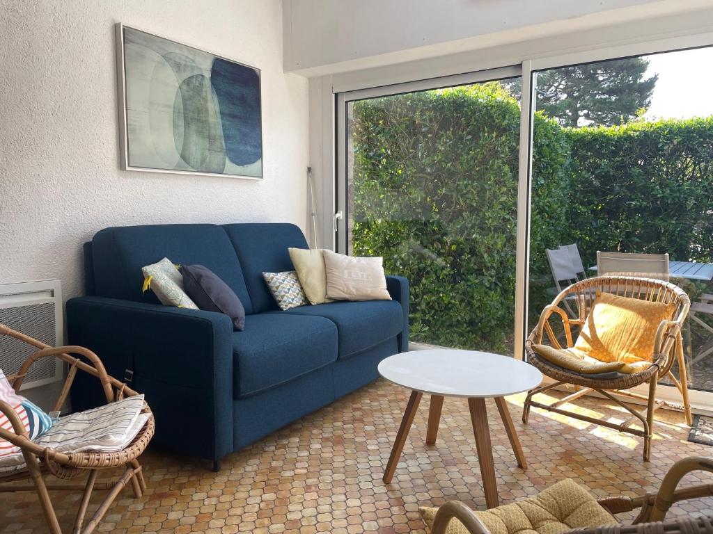 un soggiorno con divano blu e tavolo di Maisons Port en Dro 1 a Carnac