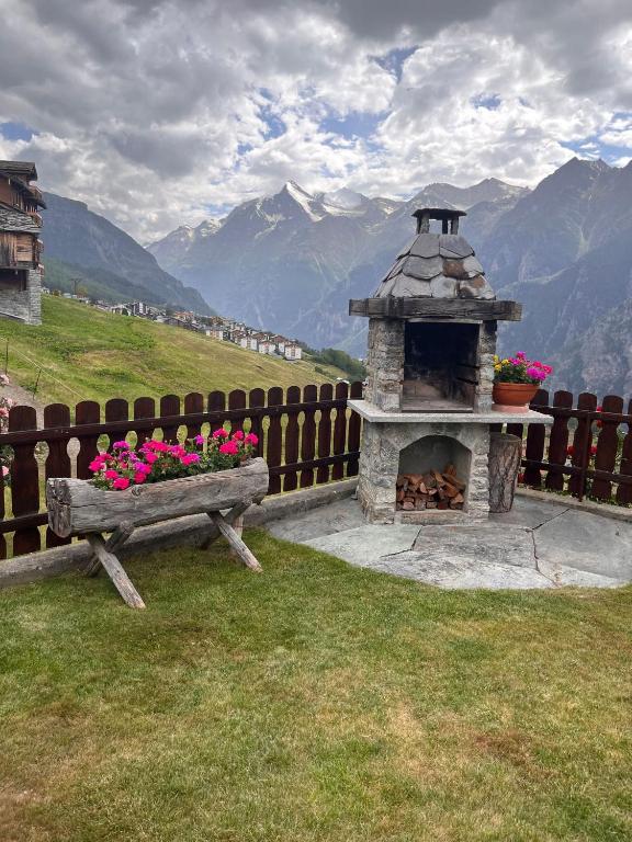 a wooden fence with a bench and a fireplace with flowers at Gaby in Grächen