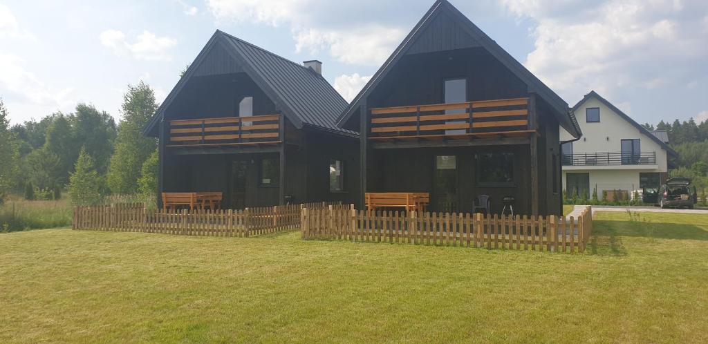 a large black house with a wooden fence in the yard at Domki Gorczyca in Płaska