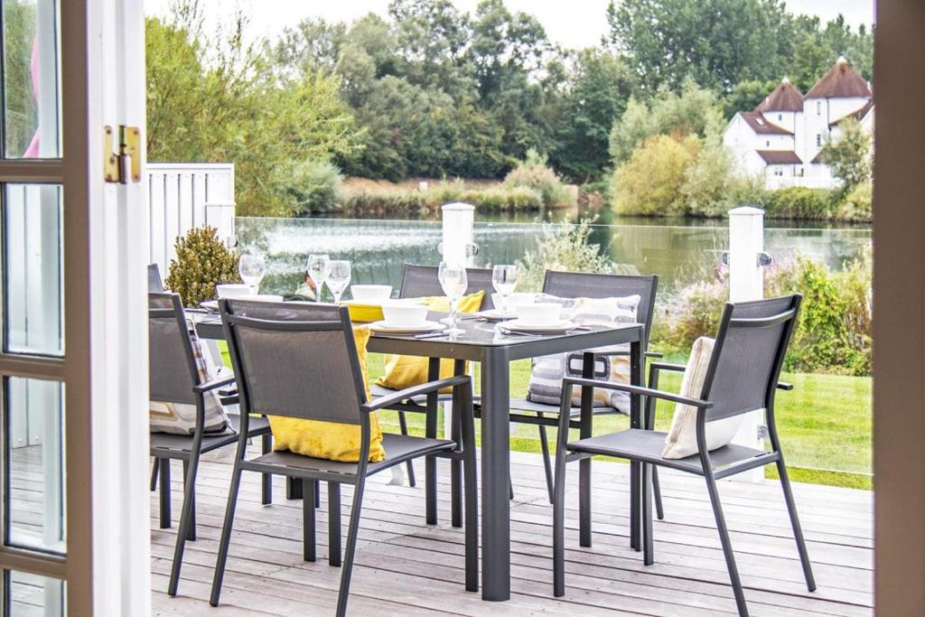 a table and chairs on a deck with a view of the water at Windrush Lake 88, Waterside in South Cerney