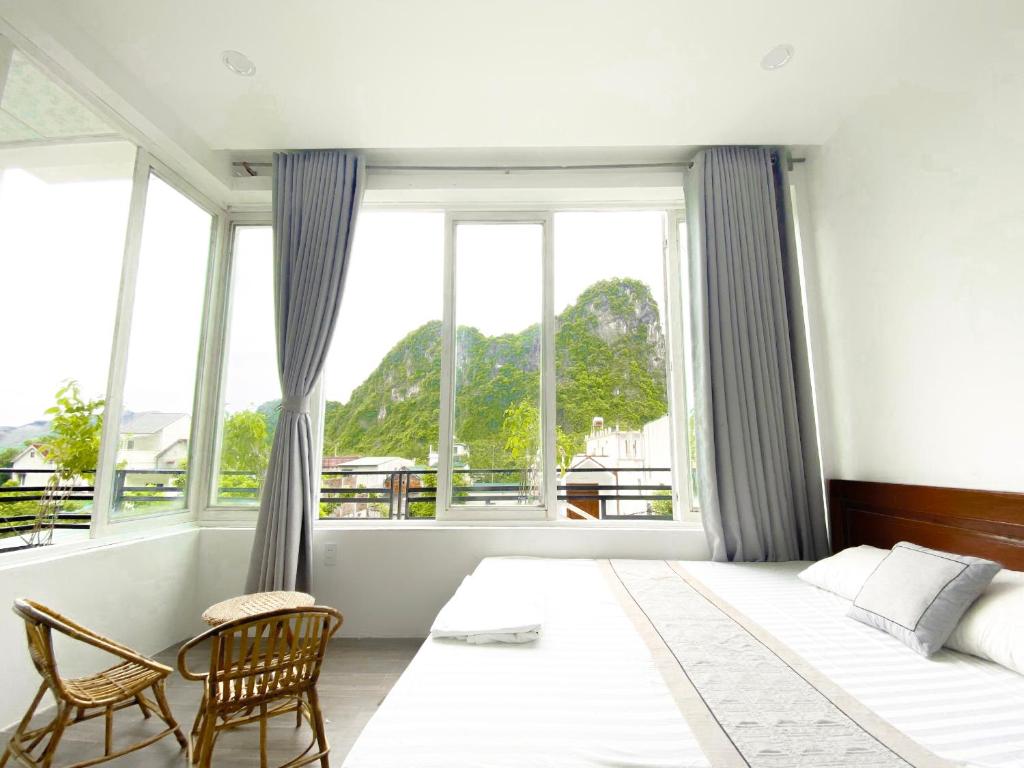 a bedroom with a bed and two chairs and windows at Hideaway Homestay in Phong Nha