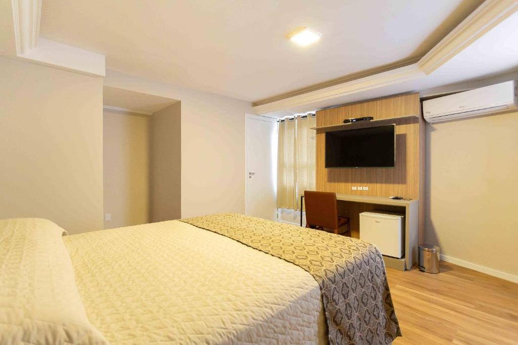 a bedroom with a bed and a flat screen tv at Hotel Dom Rafael Executivo in Santa Maria