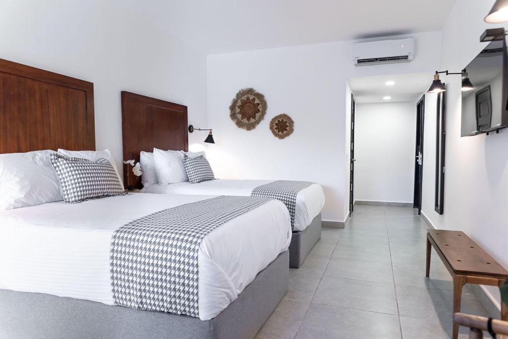2 Betten in einem Hotelzimmer mit weißen Wänden in der Unterkunft Hotel Vista Lago 