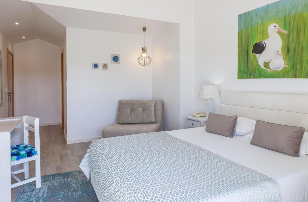 a bedroom with a white bed and a chair at Boutique Hotel Casa do Outeiro - Arts & Crafts in Batalha