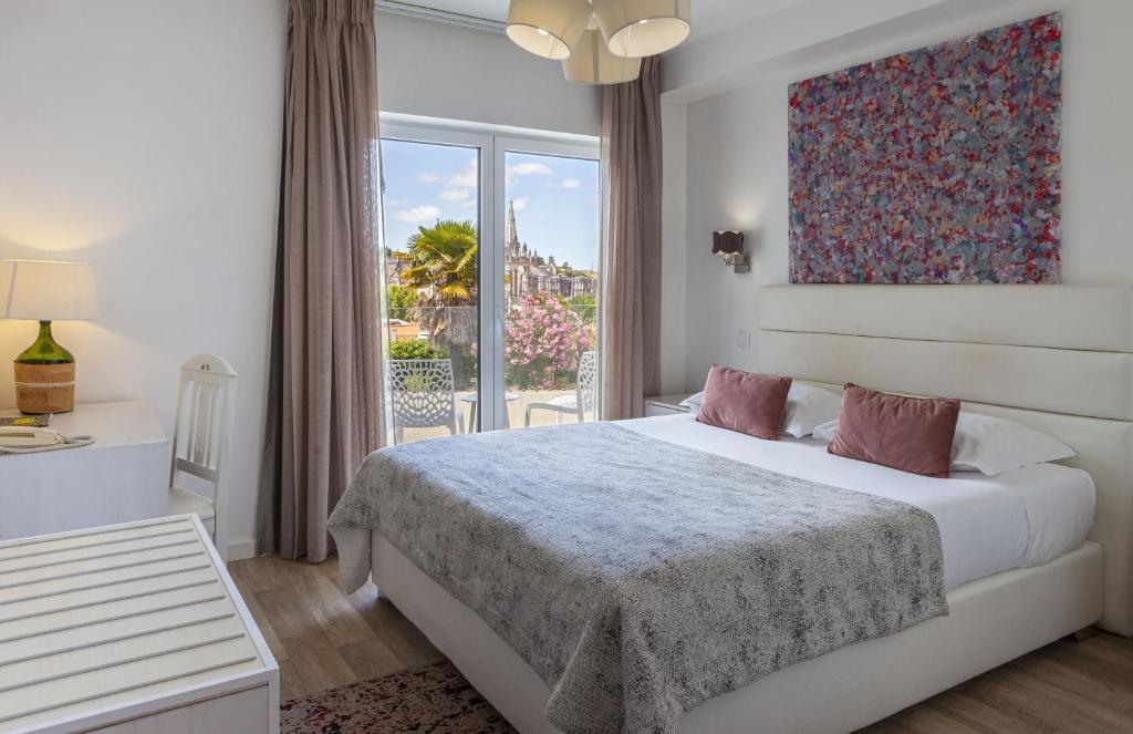 a bedroom with a bed and a large window at Boutique Hotel Casa do Outeiro - Arts & Crafts in Batalha