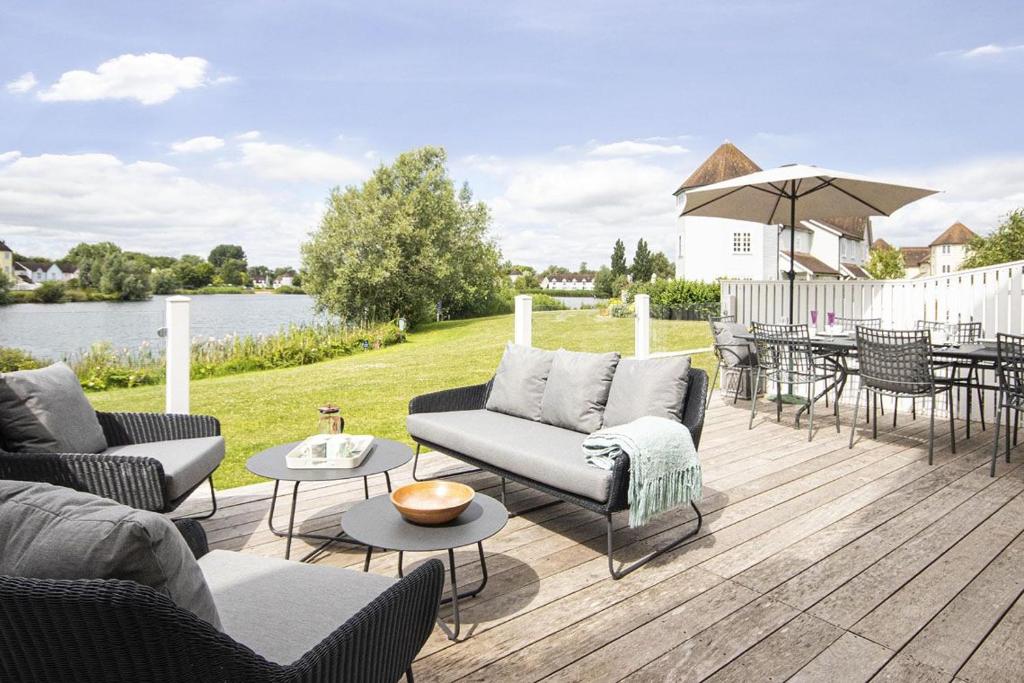 a patio with couches and tables and a table with an umbrella at Windrush Lake 89, Lodge View - P in South Cerney