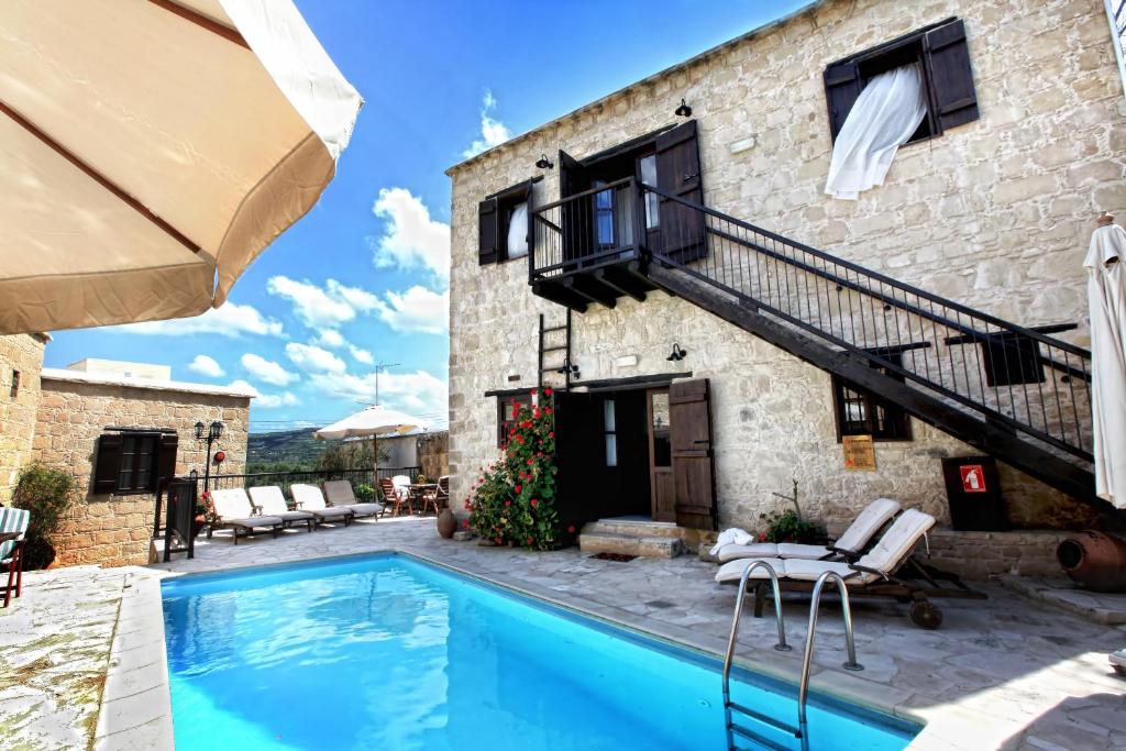 une villa avec une piscine en face d'un bâtiment dans l'établissement Leonidas Village Houses, à Goudhi