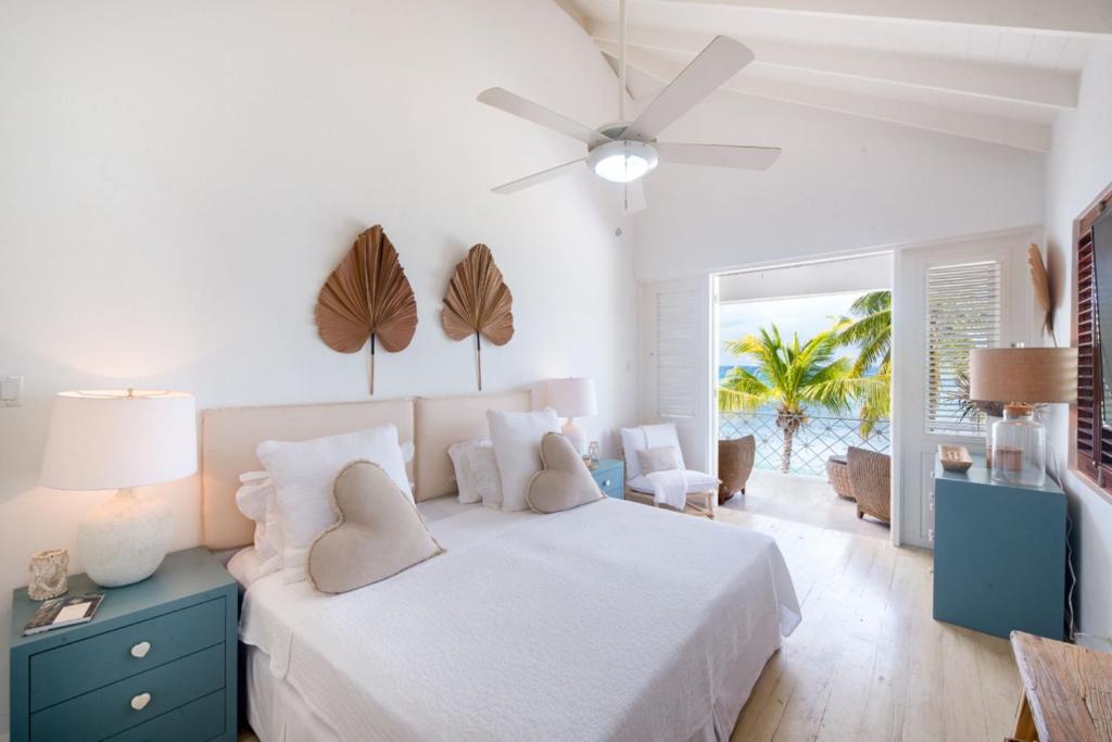 a white bedroom with a bed and a palm tree at Exceptional Beachfront Living - Milord Sunsets home in Saint James