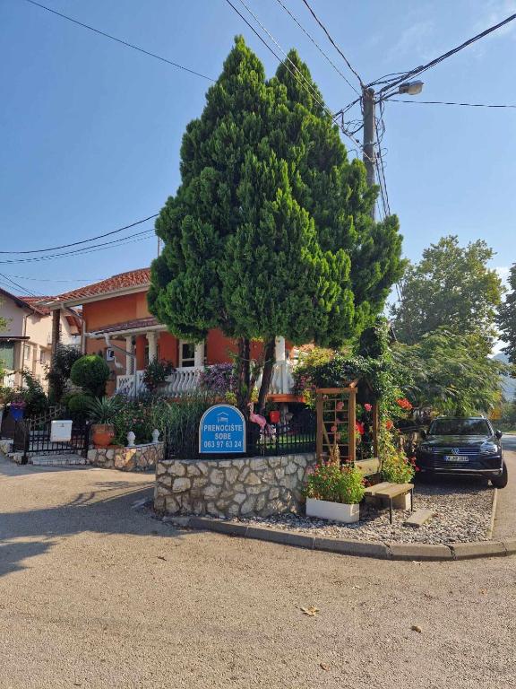 a large tree in front of a building with a car at Apartment Kula in Gračanica