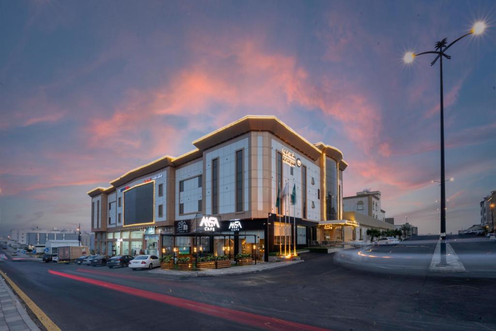 a large building on a city street at dusk at Masharef Abha Suites in Abha