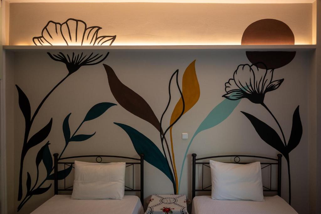a bedroom with two beds with flowers painted on the wall at Ιlias rooms in Patra