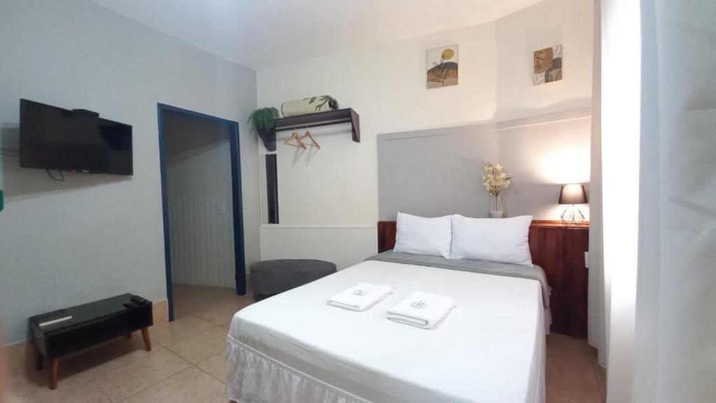 a bedroom with a white bed and a tv at Suíte Charmosa em Hospedaria no Centro in Ouro Preto