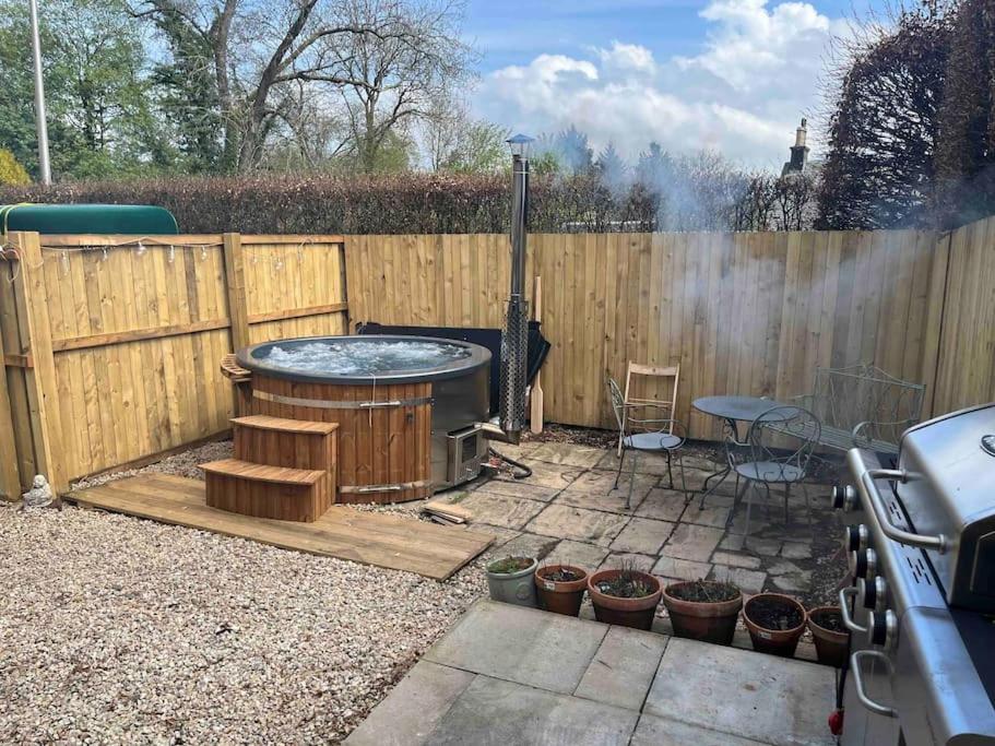 un patio trasero con bañera de hidromasaje junto a una valla de madera en Annexe Lodge cottage in Drymen, en Drymen