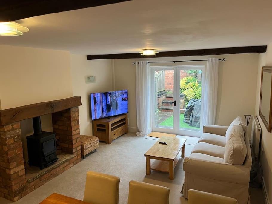 a living room with a couch and a fireplace and a tv at The Old Coach House in Stratford-upon-Avon