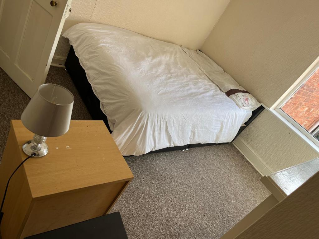 a small bed in a small room with a lamp at Iphy’s address in Wolverhampton