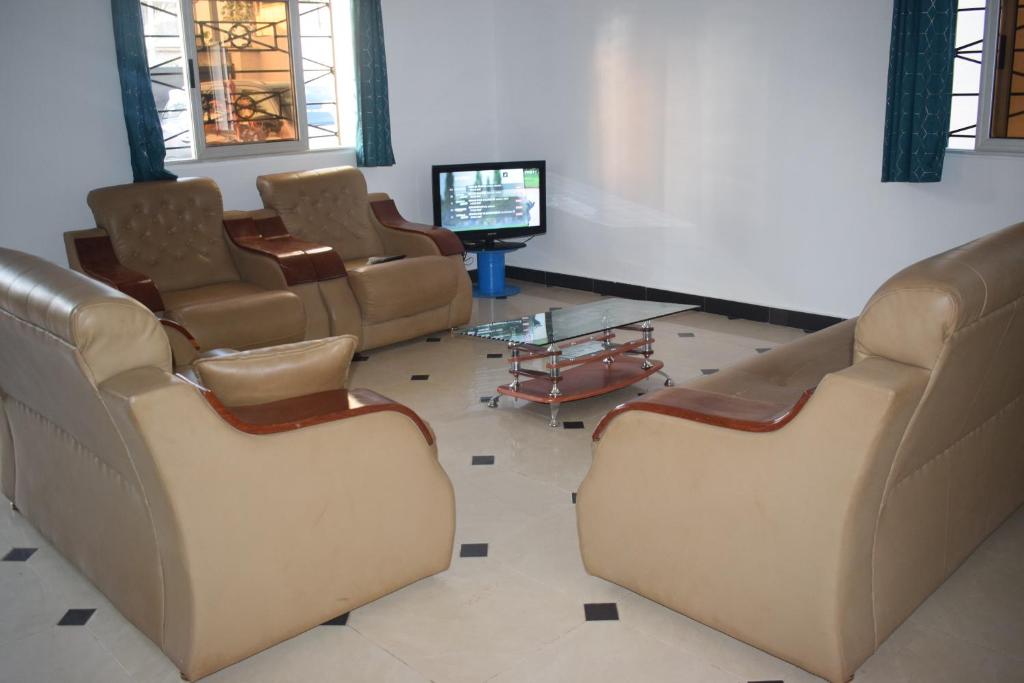 a waiting room with brown leather chairs and a tv at Villa Duplex à Arconville in Cotonou