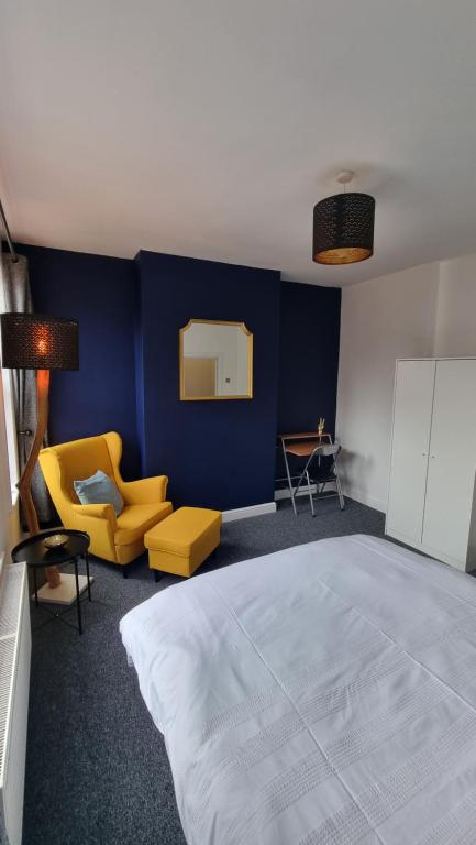 a bedroom with a large bed and a yellow chair at En Suite room with kitchen facilities in Nottingham