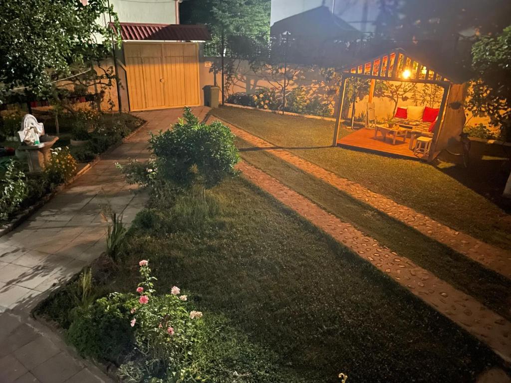 um jardim à noite com um gazebo no quintal em Happy Corner Guest House em Shkodër