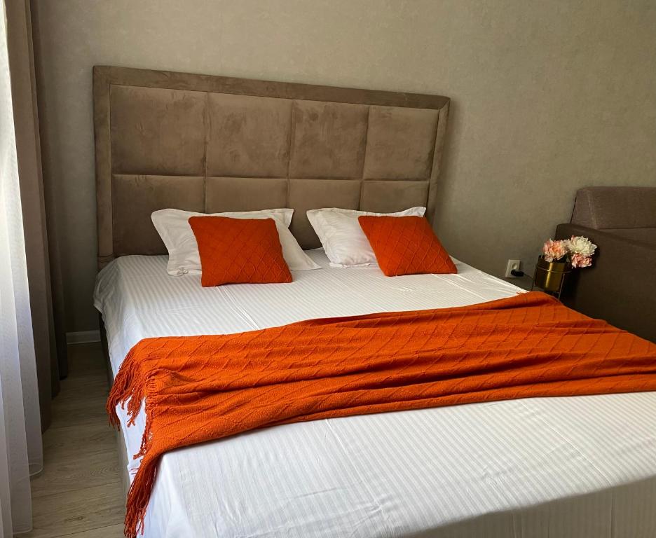 a large bed with two orange pillows on it at Уютная квартира на ЭКСПО in Prigorodnyy