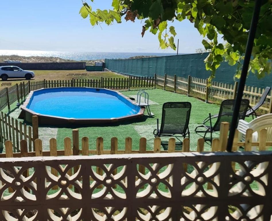 einen Hinterhof mit einem Pool und einem Zaun in der Unterkunft Casa Lobadiz, en primera línea de playa, Doniños in Vila Da Area