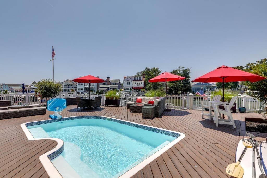 a swimming pool on a deck with tables and umbrellas at Waterfront Ocean City Escape with Large Deck, Pool! in Ocean City