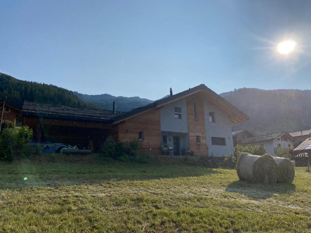 two hay bales in a field in front of a house at Aux Grands-Vergers in Bruson