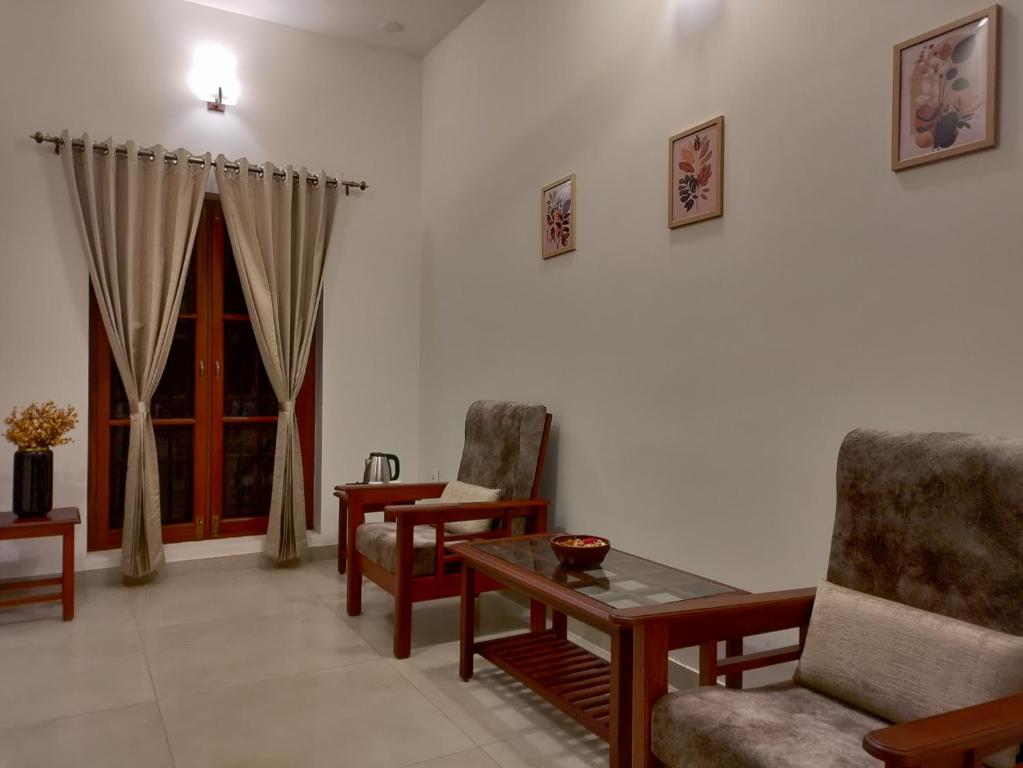a living room with chairs and a table and a window at The Cana's Coorg in Ammatti