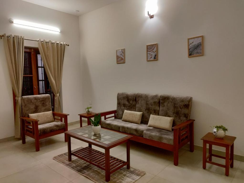 a living room with a couch and two chairs and a table at The Cana's Coorg in Ammatti