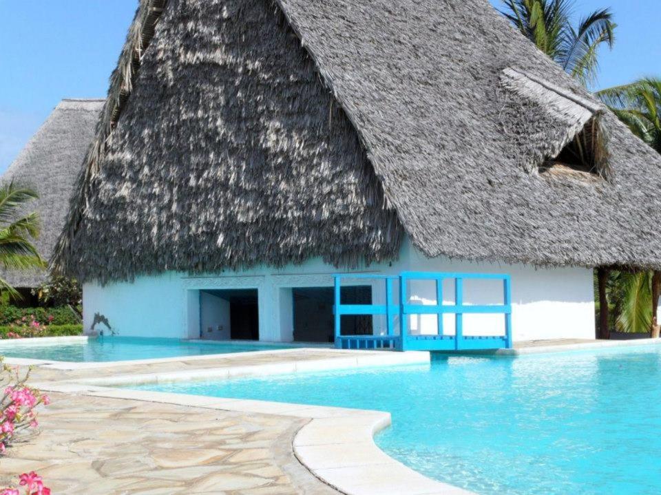 un complejo con techo de paja y piscina en Private cottages @ Karibuni Villas en Malindi