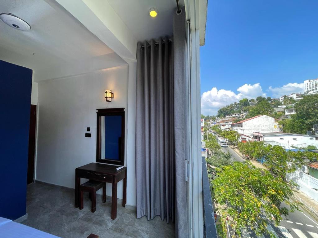 een kamer met een spiegel en een raam met uitzicht bij Kandy City Inn in Kandy